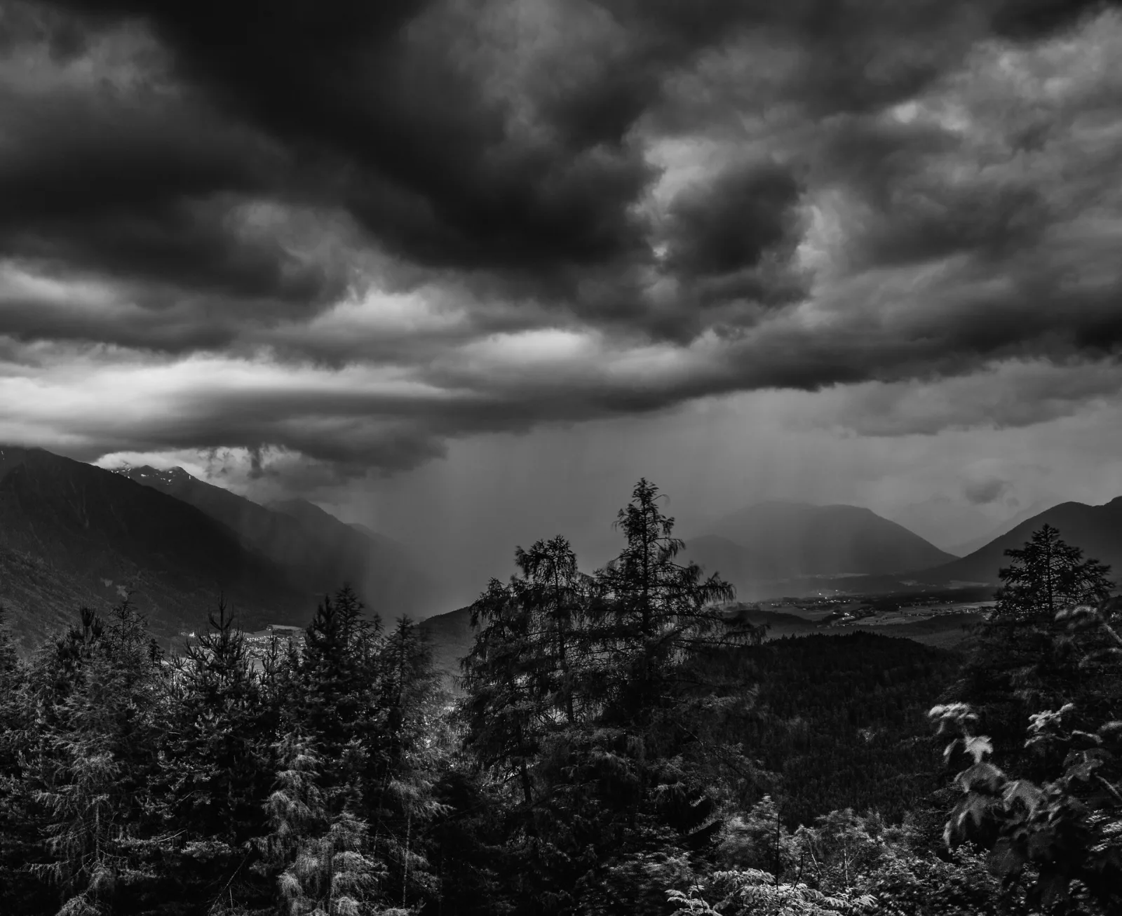 Black and white mountain forest under storm cloud, Austria